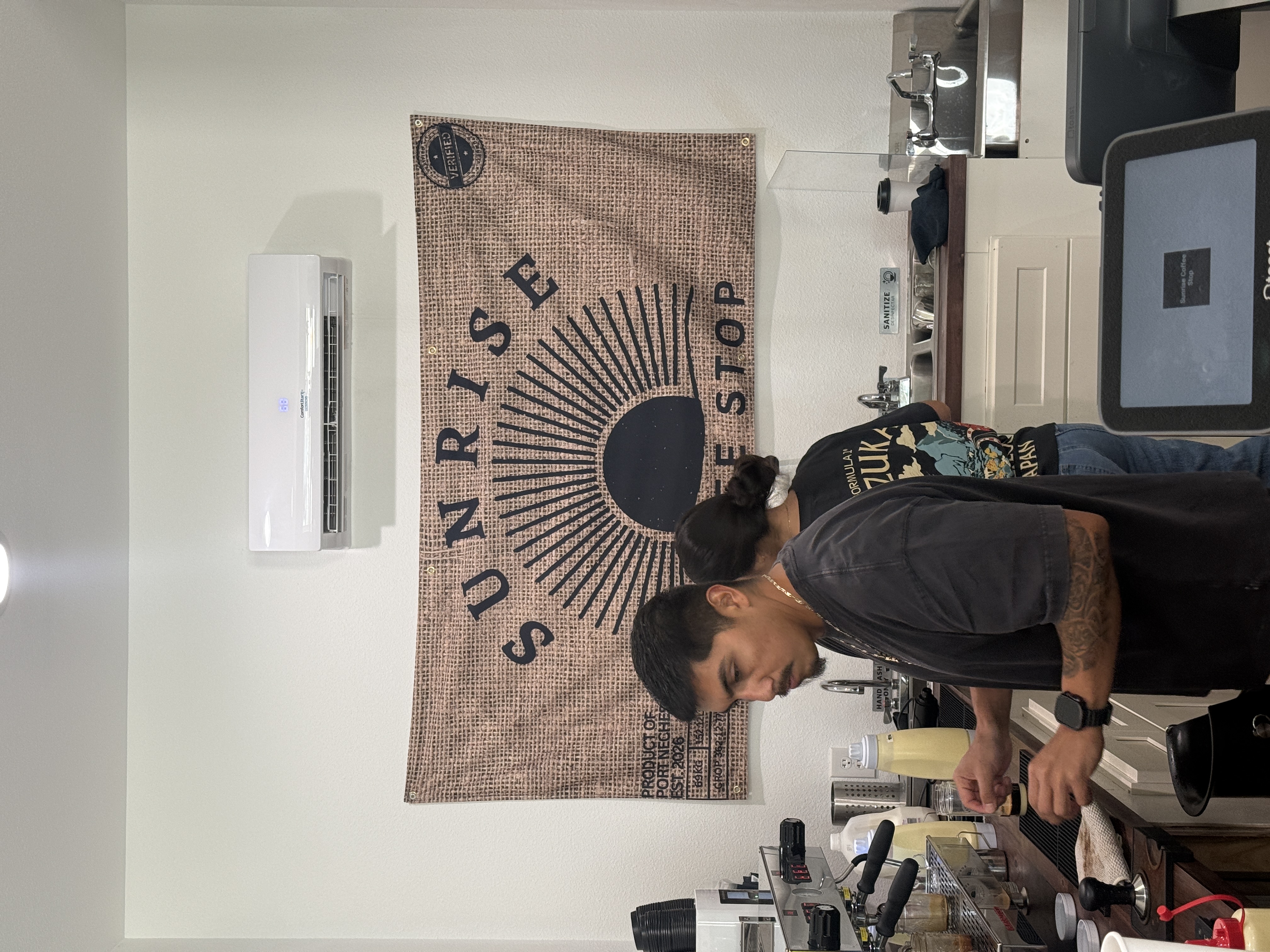 Baristas making drinks under the Sunrise Coffee Stop banner
