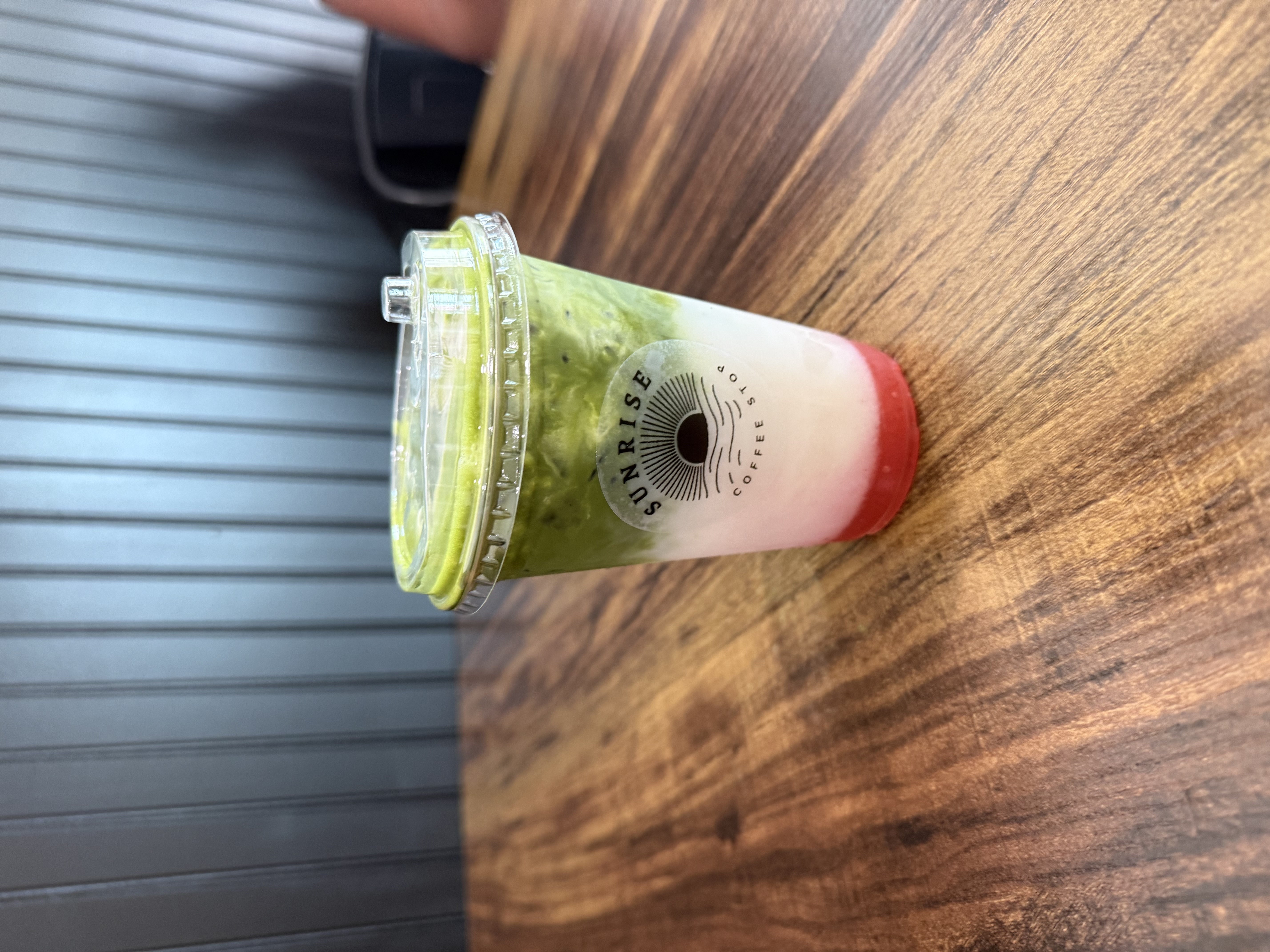 An iced strawberry matcha latte on a wood table